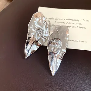 Vue détaillée des boucles d'oreilles vintage en métal argenté en forme de feuille plissée
