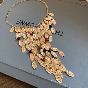 Close-up detail of vintage gold pleated oval fringe necklace with red and black beads.