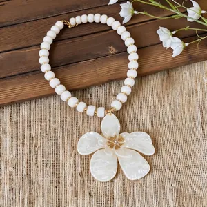 Elegant white beaded necklace with a large pearly flower pendant and gold accents