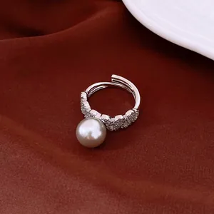 Elegant detail shot of a lace pearl ring with sparkling crystals on dark red fabric.