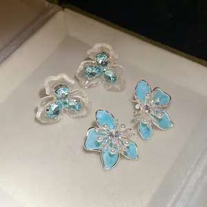 Elegante 925 Silberohrstecker mit Zirkonia Perlen und blauen Emaille Blumen Details.