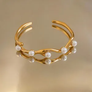Detailansicht eines vintage Goldarmreifs mit gewelltem Design und weißen Perlen.