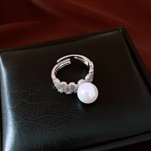 Macro view of elegant silver lace ring with large white pearl on black leather box