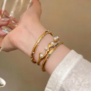 Detailansicht von goldenen Edelstahlarmbändern mit Perlen und bunten Strasssteinen
