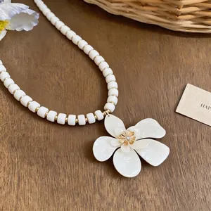 Elegant holiday style white beaded necklace with large flower pendant and diamond center