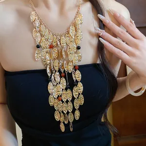 Close-up of vintage gold pleated leaf tassel necklace with red beads worn on a model