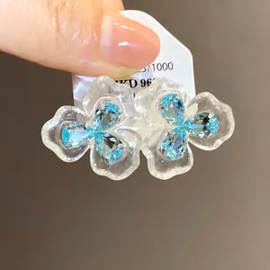 Nahaufnahme der durchscheinenden Blumenohrstecker mit leuchtend blauen Zirkonsteinen
