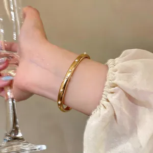 Detailaufnahme eines goldenen Armreifens aus Edelstahl mit eingelegten Perlen