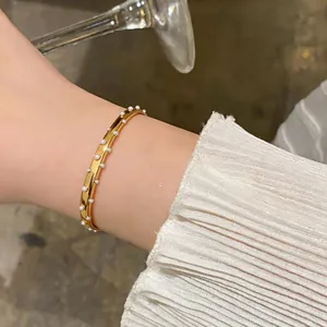 Nahaufnahme eines goldenen Edelstahl-Armreifs mit feinen Perlen-Akzenten am Handgelenk