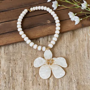 Close-up detail of a white acrylic flower pendant with beads, beach vacation style jewelry