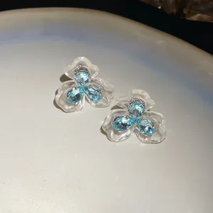 Nahaufnahme eleganter Blumenohrstecker mit durchsichtigen Blüten und blauen Zirkon