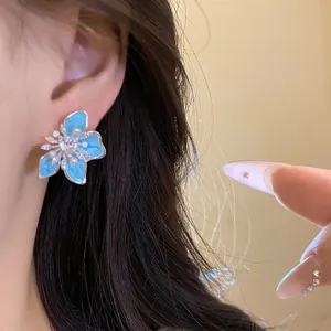 Detailansicht der eleganten blauen Emaille-Blumenohrringe mit Perlen am Modellohr
