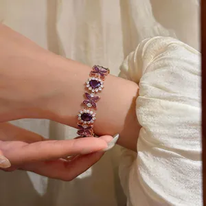 Primo piano di un elegante bracciale con zirconi viola a cuore e fiori in finitura oro rosa