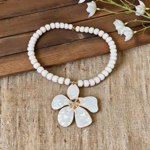 Detail view of a white flower pendant necklace with elegant beads for vacation