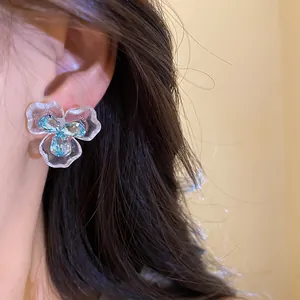 Detailansicht von Blumen-Ohrsteckern mit blauem Zirkonia und Emaille-Blütenblättern