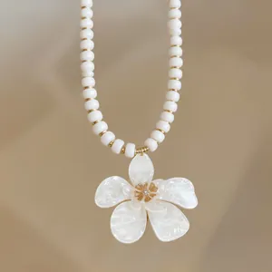 Close-up of white beaded necklace with elegant white flower pendant for vacation