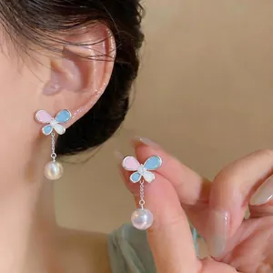 Butterfly stud earrings with pastel enamel and dangling pearl detail