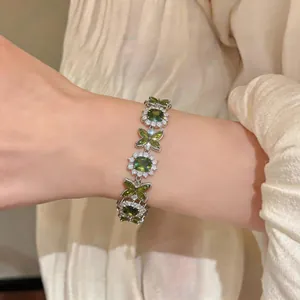 Primo piano di un elegante braccialetto in zircone verde con motivi di fiori e farfalle