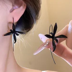 Detailed macro view of elegant black orchid-shaped metal spray paint drop earrings.