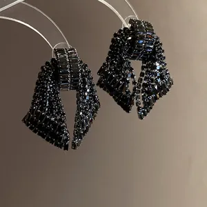 Detailed macro view of elegant black rhinestone bow-shaped earrings with a sparkly finish