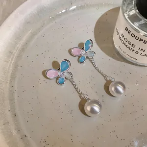 Close-up of elegant butterfly zircon earrings featuring silver tassels and white pearls