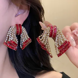 Oversized sparkling red zircon bow earrings for women with elegant golden finish.