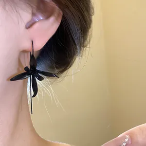 Detailed view of an elegant black flower-shaped metal spray-painted earring worn on the ear