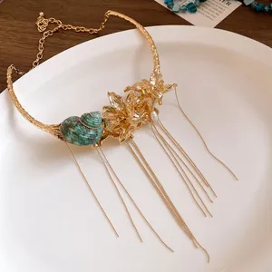 Close-up detail of vintage gold choker with shell and tassel chains in floral design.