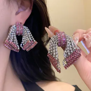 Detail of sparkly pink and white zircon bow earrings worn on ear and held by hand.
