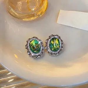 Elegant vintage court style oval green resin stud earrings with sparkling rhinestone halo