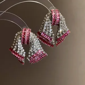 Close-up detail showing intricate pink and white zircon stones on bow earrings