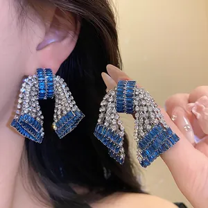 Detailed shot of sparkling blue and silver rhinestone bow earrings worn on the ear