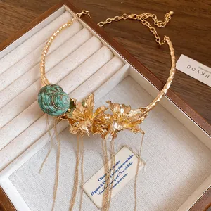 Close-up of a vintage gold choker necklace with detailed shell and floral tassels