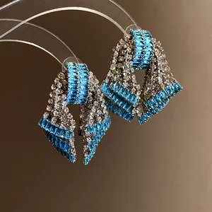 Close-up detail of bow-shaped earrings featuring blue and clear baguette cubic zirconia stones.