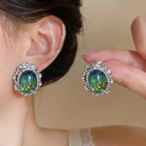 Exquisite close-up of vintage oval earrings with green resin center and rhinestone border