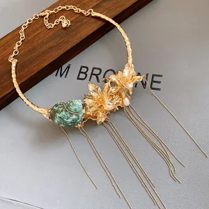 Detail of vintage gold choker necklace with green shell, flowers and long tassels