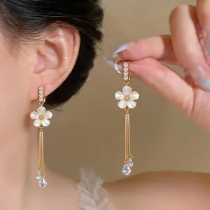Close-up of elegant flower clip-on earrings with long zircon tassels in gold finish