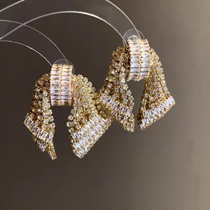 Detailed view of gold bow earrings with shimmering zirconia baguette stones.
