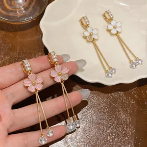 Close-up of pink and white zircon flower tassel ear clips on warm wooden background