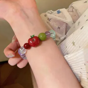Close-up of a sweet resin apple beaded bracelet with colorful stone beads worn on a wrist