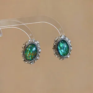 Vintage court style oval resin earrings with rhinestone border and iridescent green finish
