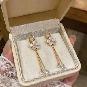 Detailed view of elegant gold floral clip-on earrings with long tassels in a gift box.