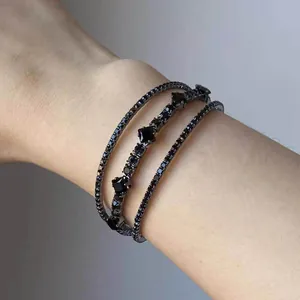 Dettaglio di un elegante bracciale a più strati con diamanti neri a rombi sul polso