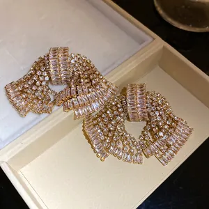 Close-up of sparkling zircon bow earrings with elegant golden finish in a jewelry box