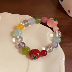 Detailed view of a sweet colorful stone beaded bracelet with red and peach resin apple charms