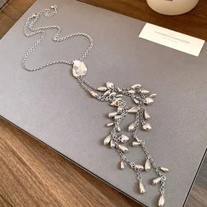 Vue détaillée d'un collier à pompon argenté avec des pendentifs goutte et cœur.