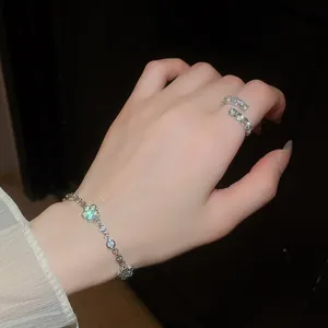 Nahaufnahme des funkelnden Blumenarmbands und des Kristallring-Sets an einer Frauenhand