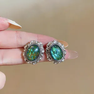 Close-up of vintage palace style oval earrings with green resin and rhinestone stones