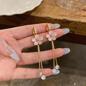 Close-up of pink enamel flower earrings with long zircon tassels in gold-tone finish