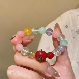 Close-up of colorful beaded bracelet with cute resin apple and peach charms.